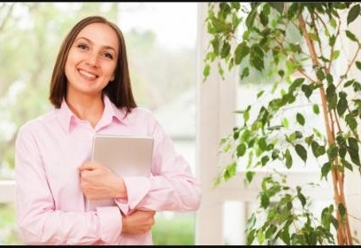 Young smiling woman with a pink shirt standing with a tablet PC in her hands